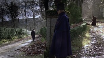 Movie still from “The Duellists” (1977), directed by Ridley Scott – A man in a top hat stands next to a stone pillar; Wide shot, Low angle