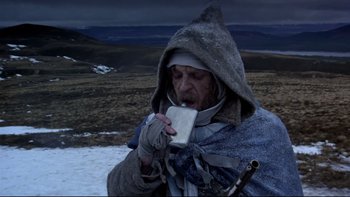 Movie still from “The Duellists” (1977), directed by Ridley Scott – An old man in a blanket drinking from a cup; Medium shot, Low angle