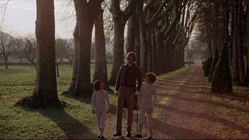Movie still from “The Duellists” (1977), directed by Ridley Scott – A man and two children standing on a dirt road; Wide shot, Low angle