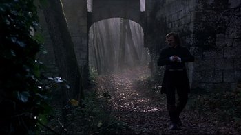 Movie still from “The Duellists” (1977), directed by Ridley Scott – A man walking through a forest near a bridge; Wide shot, Low angle