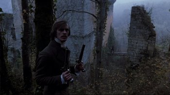 Movie still from “The Duellists” (1977), directed by Ridley Scott – A man holding a gun while standing next to a tree; Medium shot, Low angle