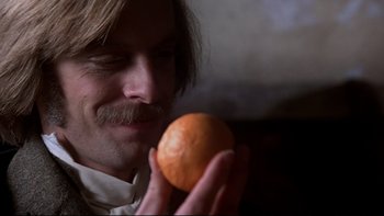 Movie still from “The Duellists” (1977), directed by Ridley Scott – A man holding an orange in front of his face; Close Up shot, Over the shoulder angle