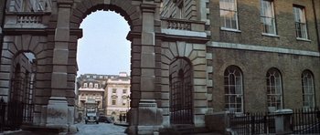 Movie still from “The Eagle Has Landed” (1976), directed by John Sturges – An archway leading to a building with a car parked in front of it; Extreme Wide shot, High angle