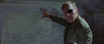 Movie still from “The Eagle Has Landed” (1976), directed by John Sturges – A man wearing a eye patch points to a map; Close Up shot, Over the shoulder angle
