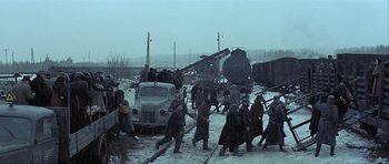 Movie still from “The Eagle Has Landed” (1976), directed by John Sturges – A group of people walking across a snow covered road; Extreme Wide shot, High angle
