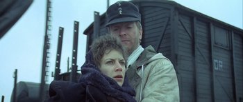 Movie still from “The Eagle Has Landed” (1976), directed by John Sturges – A man and a woman standing next to each other in front of a building; Close Up shot, Low angle