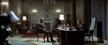 Movie still from “The Eagle Has Landed” (1976), directed by John Sturges – A man sitting at a desk in a room; Wide shot, High angle