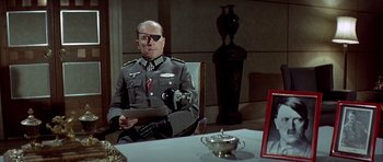 Movie still from “The Eagle Has Landed” (1976), directed by John Sturges – A man in uniform sitting at a dining table; Medium shot, Over the shoulder angle