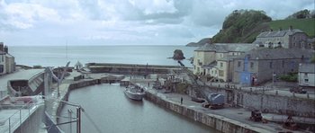 Movie still from “The Eagle Has Landed” (1976), directed by John Sturges – A boat is docked at a pier near a body of water; Extreme Wide shot, High angle