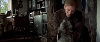 Movie still from “The Eagle Has Landed” (1976), directed by John Sturges – A man sitting in front of a tree with a dog; Close Up shot, Over the shoulder angle