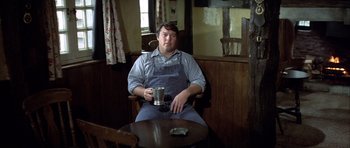Movie still from “The Eagle Has Landed” (1976), directed by John Sturges – A man sitting at a table holding a mug; Medium shot, High angle