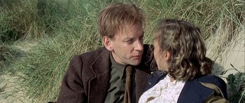 Movie still from “The Eagle Has Landed” (1976), directed by John Sturges – A man and a woman sitting on the grass; Close Up shot, Over the shoulder angle