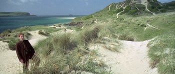 Movie still from “The Eagle Has Landed” (1976), directed by John Sturges – A grassy area with a beach and a body of water in the background; Extreme Wide shot, High angle