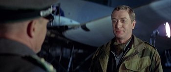 Movie still from “The Eagle Has Landed” (1976), directed by John Sturges – A person standing in front of an airplane; Close Up shot, Low angle