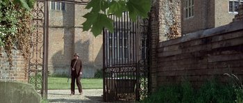 Movie still from “The Eagle Has Landed” (1976), directed by John Sturges – A man standing in front of an iron gate; Wide shot, Over the shoulder angle