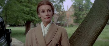 Movie still from “The Eagle Has Landed” (1976), directed by John Sturges – A woman in a tan coat standing in front of a tree; Close Up shot, Over the shoulder angle