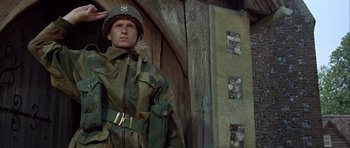 Movie still from “The Eagle Has Landed” (1976), directed by John Sturges – A man in a military uniform standing in front of a building; Medium shot, Low angle