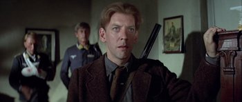 Movie still from “The Eagle Has Landed” (1976), directed by John Sturges – A person holding a gun in a room; Close Up shot, Low angle