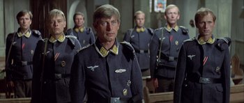 Movie still from “The Eagle Has Landed” (1976), directed by John Sturges – A group of men in uniforms standing next to each other; Medium shot, Low angle
