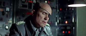 Movie still from “The Eagle Has Landed” (1976), directed by John Sturges – An older man wearing a leather jacket and a pair of sunglasses; Close Up shot, Low angle