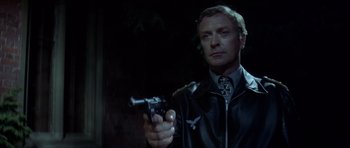 Movie still from “The Eagle Has Landed” (1976), directed by John Sturges – A man holding a gun while standing in a dark room; Close Up shot, Low angle