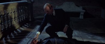 Movie still from “The Eagle Has Landed” (1976), directed by John Sturges – A man kneeling down next to a dead body; Medium shot, High angle