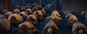 Movie still from “The Egyptian” (1954), directed by Michael Curtiz – A group of men kneeling down on the ground; Wide shot, High angle