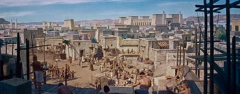 Movie still from “The Egyptian” (1954), directed by Michael Curtiz – An ancient city with a lot of people sitting on the ground; Extreme Wide shot, High angle