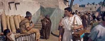 Movie still from “The Egyptian” (1954), directed by Michael Curtiz – A group of people standing next to each other on a street; Medium shot, Over the shoulder angle