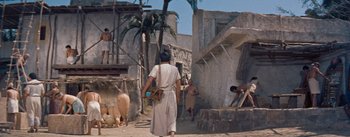 Movie still from “The Egyptian” (1954), directed by Michael Curtiz – A group of people walking down a dirt road; Wide shot, High angle