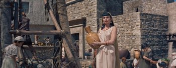 Movie still from “The Egyptian” (1954), directed by Michael Curtiz – A woman dressed as cleopatra holding an urn; Medium shot, Low angle