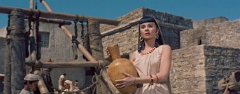 Movie still from “The Egyptian” (1954), directed by Michael Curtiz – A woman holding a large vase in her hands; Close Up shot, Low angle