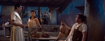 Movie still from “The Egyptian” (1954), directed by Michael Curtiz – A woman holding a knife in front of a man holding a vase; Medium shot, Low angle