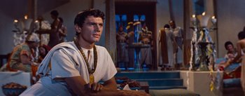 Movie still from “The Egyptian” (1954), directed by Michael Curtiz – A man sitting in front of a group of people; Medium shot, Low angle