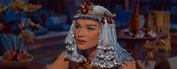 Movie still from “The Egyptian” (1954), directed by Michael Curtiz – A woman in a silver headdress and a gold necklace; Close Up shot, Over the shoulder angle
