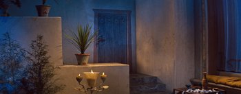 Movie still from “The Egyptian” (1954), directed by Michael Curtiz – A plant and candles in front of a door; Wide shot, Low angle