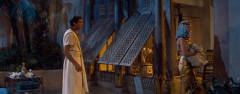 Movie still from “The Egyptian” (1954), directed by Michael Curtiz – A man standing in front of a building with many windows; Wide shot, Low angle