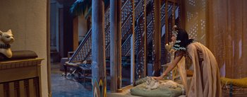 Movie still from “The Egyptian” (1954), directed by Michael Curtiz – A woman sitting on a bed with a dog in a room; Wide shot, Low angle