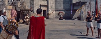 Movie still from “The Egyptian” (1954), directed by Michael Curtiz – A man dressed as a roman soldier in front of a statue; Wide shot, High angle