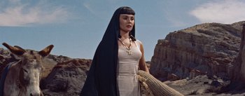 Movie still from “The Egyptian” (1954), directed by Michael Curtiz – A woman in a long dress and a black headscarf; Medium shot, Low angle