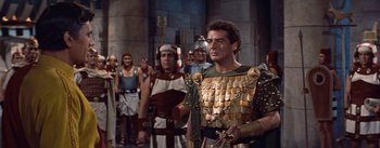 Movie still from “The Egyptian” (1954), directed by Michael Curtiz – A group of men standing next to each other in roman garb; Medium shot, Over the shoulder angle