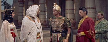 Movie still from “The Egyptian” (1954), directed by Michael Curtiz – A man in a costume talking to an older man in an egyptian costume; Medium shot, Over the shoulder angle