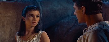 Movie still from “The Egyptian” (1954), directed by Michael Curtiz – A man and a woman standing next to each other in front of a stone wall; Close Up shot, Over the shoulder angle