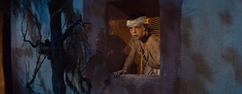Movie still from “The Egyptian” (1954), directed by Michael Curtiz – A young boy wearing a bandanna looking out of a window; Medium shot, High angle