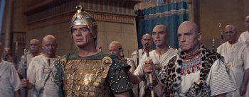 Movie still from “The Egyptian” (1954), directed by Michael Curtiz – A group of men dressed in ancient roman clothing; Medium shot, Over the shoulder angle
