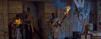 Movie still from “The Egyptian” (1954), directed by Michael Curtiz – A man holding a fire in front of an egyptian wall; Wide shot, High angle
