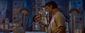 Movie still from “The Egyptian” (1954), directed by Michael Curtiz – A man is looking into a mirror in a room with statues; Medium shot, Over the shoulder angle