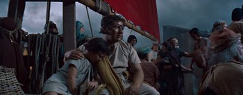 Movie still from “The Egyptian” (1954), directed by Michael Curtiz – A man and a woman sitting next to each other on a boat; Medium shot, Low angle