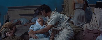 Movie still from “The Egyptian” (1954), directed by Michael Curtiz – A man in a white shirt is holding a spear; Medium shot, High angle