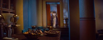 Movie still from “The Egyptian” (1954), directed by Michael Curtiz – A woman dressed as cleopatra stands in front of a bowl of fruit; Wide shot, Low angle